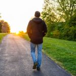 Man walking on a peaceful path as the sun sets, reflecting calm and balance