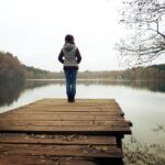 Menopause Awareness Month - Understanding the Change is a picture of a woman standing alone at dusk by a lake