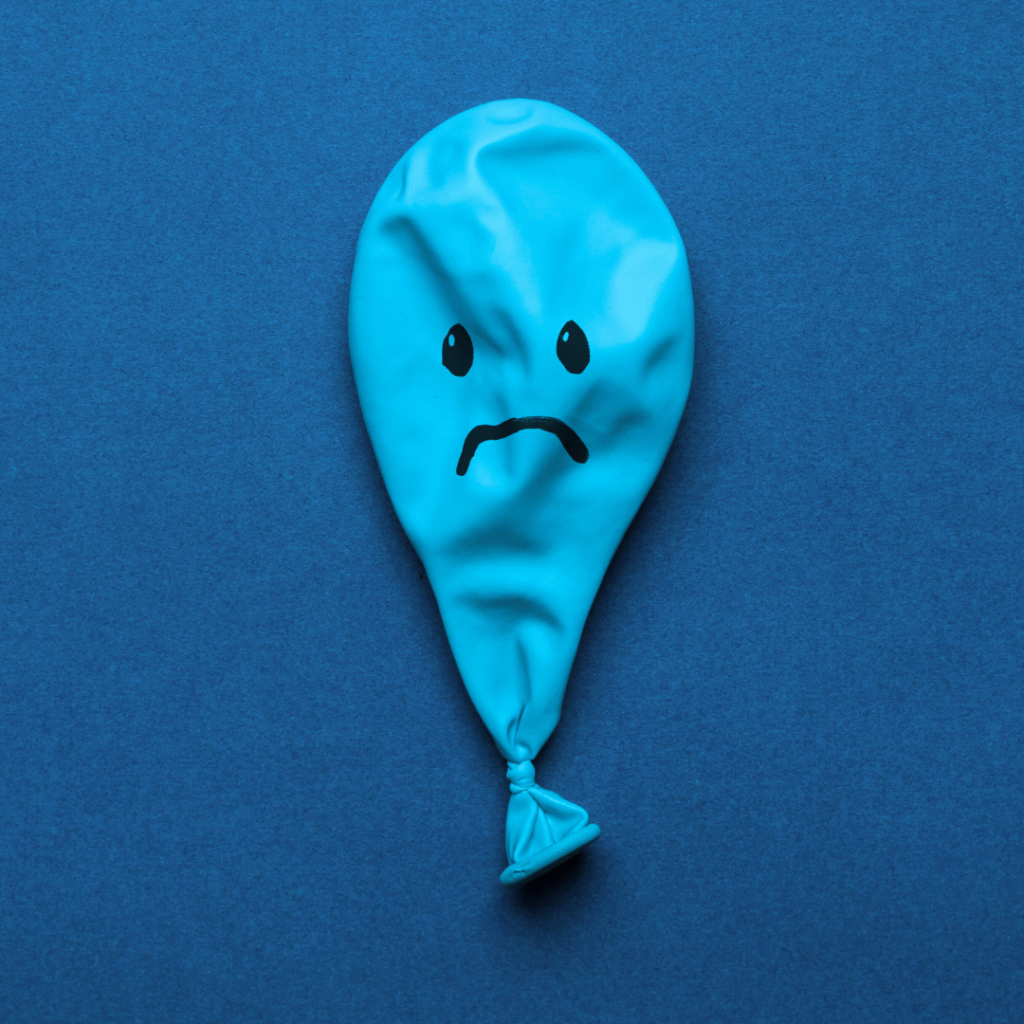 Flat balloon with a sad face drawn on