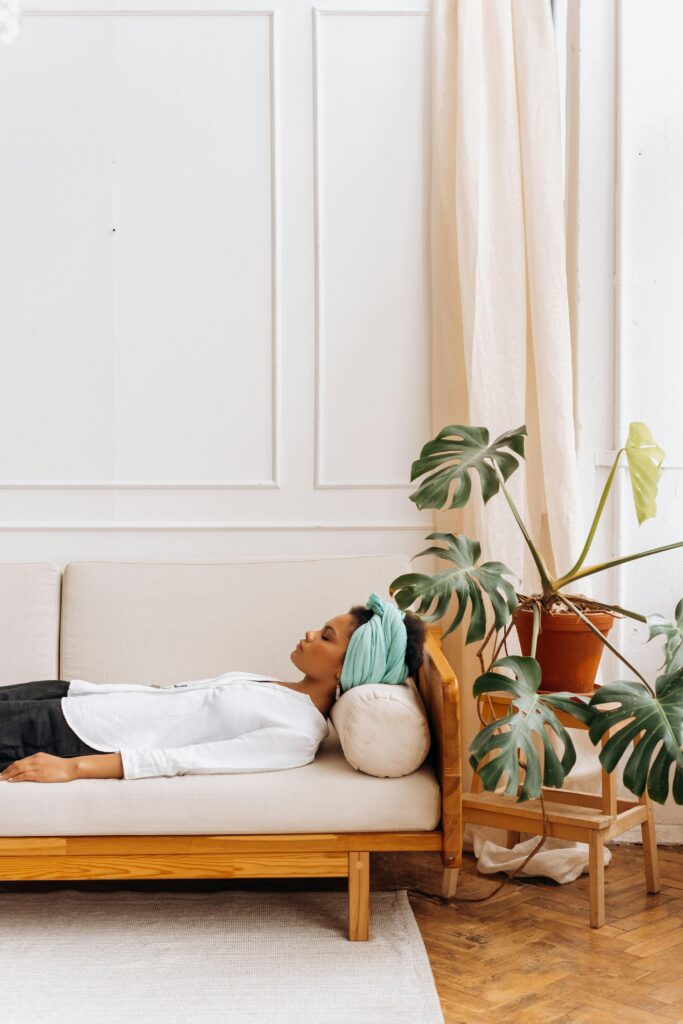 Woman laying on the sofa with her eyes closed looking relaxed